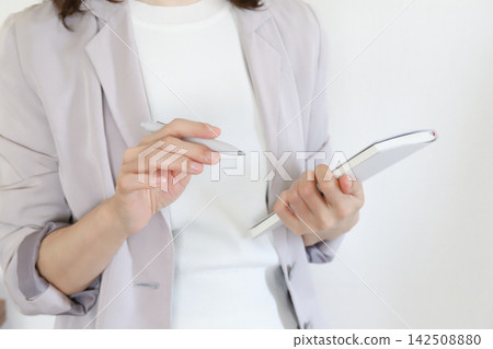 一位女商人正在開會時用筆記本做筆記。 142508880