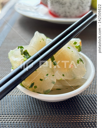 Chopsticks holding a piece of translucent pickled vegetable Chopsticks holding a piece of translucent pickled vegetable 142509822