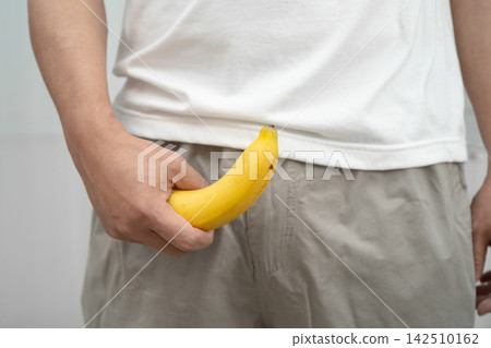 Male stands holding a banana, penis health. Male stands holding a banana, penis health. 142510162