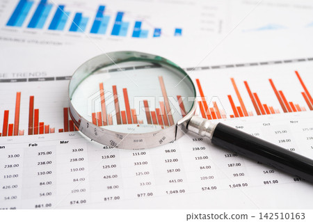 Magnifying glass on data business graphs paper. Magnifying glass on data business graphs paper. 142510163