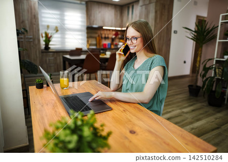 Woman working from home using laptop and smartphone 142510284