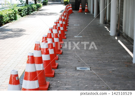 Red traffic cones lined up neatly on the sidewalk Red traffic cones lined up neatly on the sidewalk 142510529