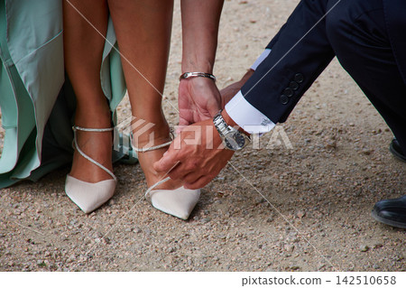 Romantic gesture of the groom adjusting the bride's elegant mint green shoes on their wedding day Romantic gesture of the groom adjusting the bride's elegant mint green shoes on their wedding day 142510658
