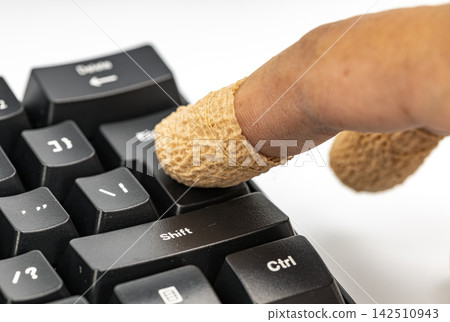 Macro shot of an injured finger covered with a bandage pressing down on a black computer keyboard shift key, symbolizing the hidden risks, dangers and consequences of a single click Macro shot of an injured finger covered with a bandage pressing down on a black computer keyboard shift key, symbolizing the hidden risks, dangers and consequences of a single click 142510943
