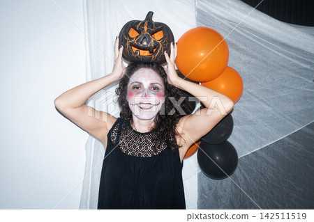 Smiling woman holding a Halloween pumpkin Smiling woman holding a Halloween pumpkin 142511519