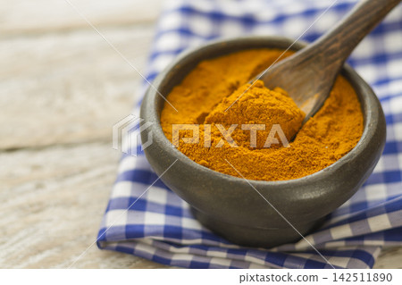 Ground turmeric in a bowl on wooden background- turmeric longa Ground turmeric in a bowl on wooden background- turmeric longa 142511890