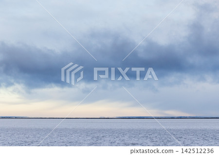 A minimalist winter seascape featuring a flat snowy shoreline A minimalist winter seascape featuring a flat snowy shoreline 142512236
