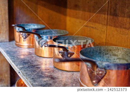 Vintage Copper Saucepans Lined Up on Rustic Wooden Shelf Vintage Copper Saucepans Lined Up on Rustic Wooden Shelf 142512373