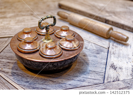 Antique Copper Egg Poacher and Rolling Pin on Parquet Table Antique Copper Egg Poacher and Rolling Pin on Parquet Table 142512375