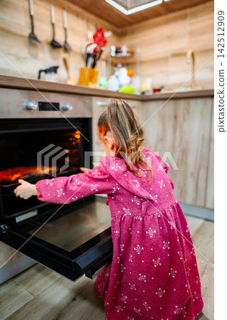 Little girl baking cookies in the oven at home Little girl baking cookies in the oven at home 142512909