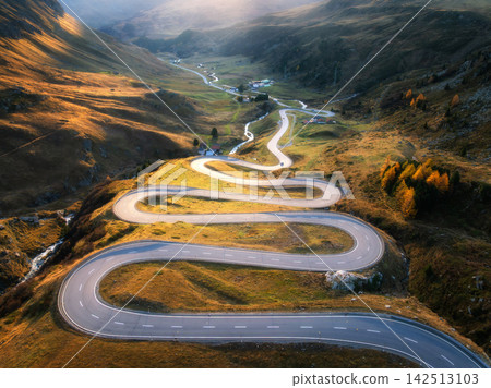 Aerial view of winding mountain road, river in alpine valley Aerial view of winding mountain road, river in alpine valley 142513103