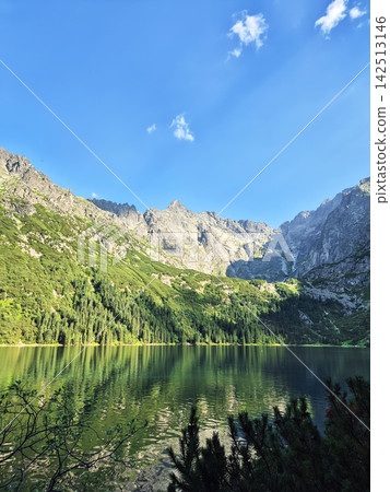 Scenic High Tatra mountains with a small forest lake beneath rugged rocky summits. Natural wilderness landscape between Poland and Slovakia. Scenic High Tatra mountains with a small forest lake beneath rugged rocky summits. Natural wilderness landscape between Poland and Slovakia. 142513146
