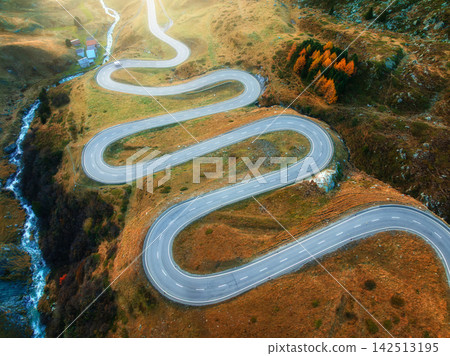 Aerial view of winding mountain road, river in alpine valley Aerial view of winding mountain road, river in alpine valley 142513195