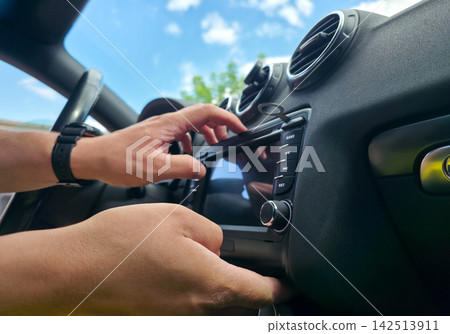 Hands using removal keys to pull car stereo from dashboard panel. Concept of car audio upgrade, auto electronics repair, vehicle installation, car service Hands using removal keys to pull car stereo from dashboard panel. Concept of car audio upgrade, auto electronics repair, vehicle installation, car service 142513911