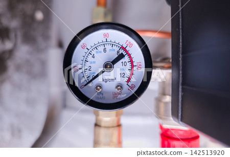 Analog pressure gauge on air compressor, copper pipes background, copy space. Industrial maintenance, engineering equipment, HVAC service, safety monitoring concept Analog pressure gauge on air compressor, copper pipes background, copy space. Industrial maintenance, engineering equipment, HVAC service, safety monitoring concept 142513920