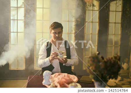 Person carefully investigates materials near illuminated window Person carefully investigates materials near illuminated window 142514764