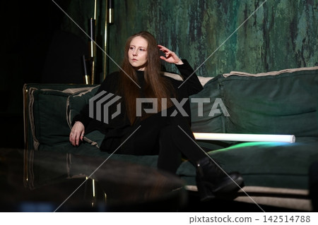 Content creator hosting podcast on comfortable emerald sofa with neon glow 142514788