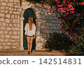 Woman Walking toward Door of Stone House 142514831