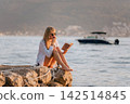 European Woman Eating Peach while Reading Book 142514845