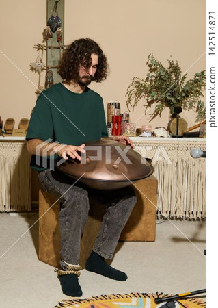 Man practicing handpan casually with socks and rug visible Man practicing handpan casually with socks and rug visible 142514871