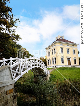 An old mansion and a white arched bridge in an autumn park. An old mansion and a white arched bridge in an autumn park. 142515399