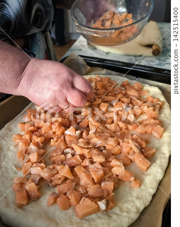 The process of making homemade pizza or a pie with red fish cubes. 142515400