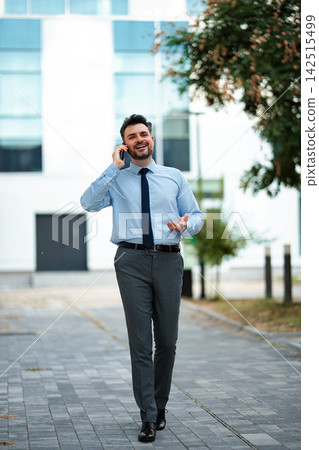 Business professional walking outdoors and talking on mobile phone Business professional walking outdoors and talking on mobile phone 142515499