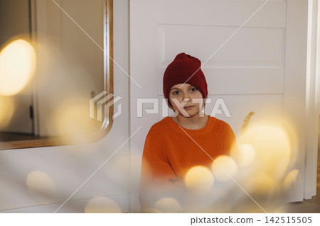 Boy in Red Beanie Sitting by Christmas Lights at Home Boy in Red Beanie Sitting by Christmas Lights at Home 142515505