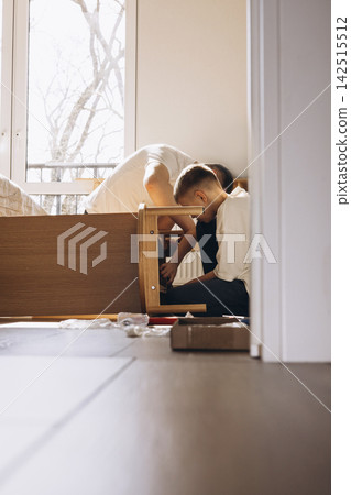Father and son assembling furniture together at home Father and son assembling furniture together at home 142515512