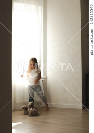 Little girl playing with a teddy bear in soft window light Little girl playing with a teddy bear in soft window light 142515546