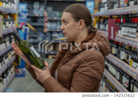 She reviews ingredients carefully. Person examines wine for additives and ethics. Individual thoughtfully reviews wine product credentials for health benefits and sustainability commitments She reviews ingredients carefully. Person examines wine for additives and ethics. Individual thoughtfully reviews wine product credentials for health benefits and sustainability commitments 142515622