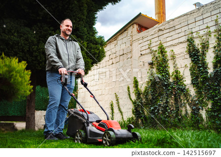 Man mowing green lawn in backyard 142515697