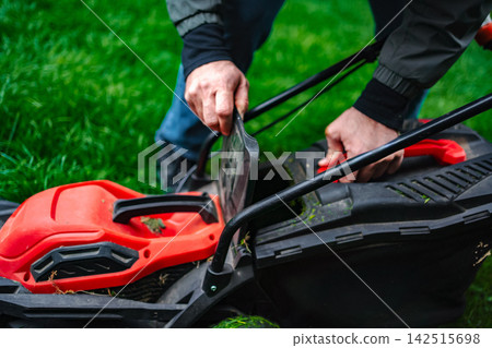 Person checking lawn mower grass bag in backyard Person checking lawn mower grass bag in backyard 142515698