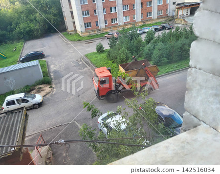 An orange garbage truck brings a huge container of construction waste to the yard. Collection and transportation of waste by municipal services. Recycling concept 142516034