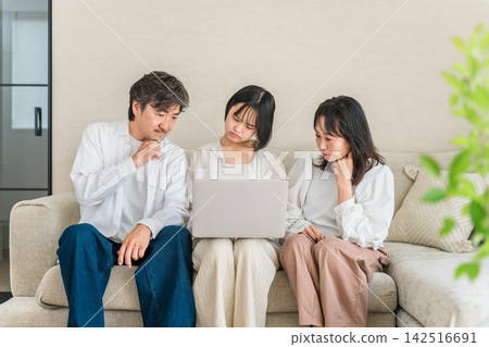 A family gathered around a computer, deep in thought; parents and children discussing career paths and future plans. A family gathered around a computer, deep in thought; parents and children discussing career paths and future plans. 142516691