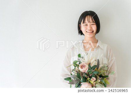 A teenage girl smiles, holding a bouquet of flowers, creating a bright and refreshing image for a special occasion. A teenage girl smiles, holding a bouquet of flowers, creating a bright and refreshing image for a special occasion. 142516965