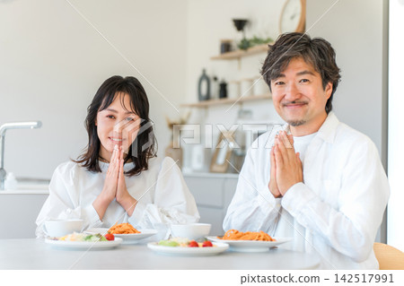 一對四十多歲的夫婦在用餐前互道「いただきます」（謝謝款待）。這對關係親密的夫婦面帶笑容地圍坐在餐桌旁。 142517991