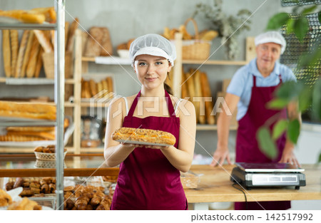 Young smiling woman baker offers to buy fresh delicious bocadillo Young smiling woman baker offers to buy fresh delicious bocadillo 142517992