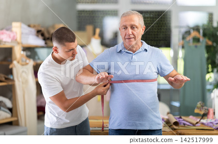 Young Tailor Taking Measurements From Elderly Man Young Tailor Taking Measurements From Elderly Man 142517999