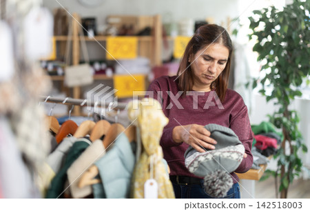 Adult woman choosing hat in clothing store Adult woman choosing hat in clothing store 142518003