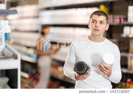 Young man buying jar of sports nutrition Young man buying jar of sports nutrition 142518087