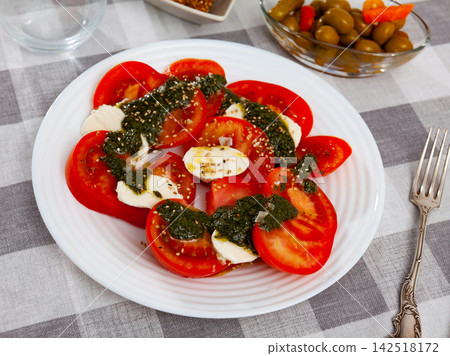 Traditional dish of Italian cuisine caprese salad with fresh tomatoes and mozzarella cheese Traditional dish of Italian cuisine caprese salad with fresh tomatoes and mozzarella cheese 142518172