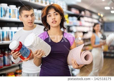 Guy and Latin girl consult about purchasing sports nutrition, enriched protein shake Guy and Latin girl consult about purchasing sports nutrition, enriched protein shake 142518175