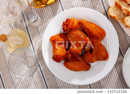 Crispy smoked chicken wings served in a flat plate Crispy smoked chicken wings served in a flat plate 142518186