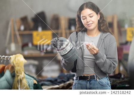 During November sales, young woman choose and buy hat During November sales, young woman choose and buy hat 142518242