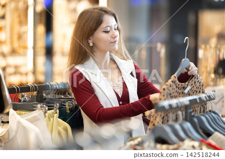 European woman choosing a warm sweater in a shopping mall 142518244