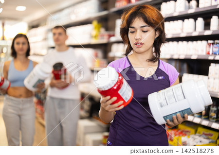 Young woman buying jar of sports nutrition Young woman buying jar of sports nutrition 142518278