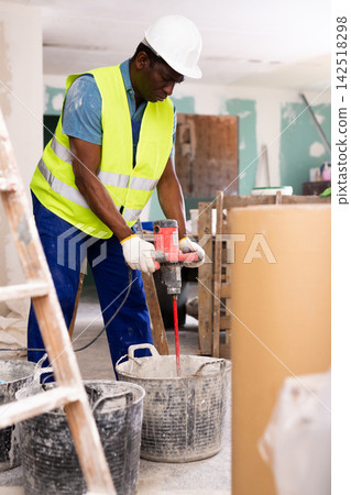 Portrait of an african american builder, working in the process of repair Portrait of an african american builder, working in the process of repair 142518298