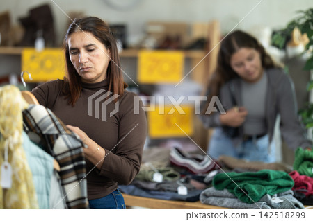 Selective Latina woman choosing something for autumn-winter in clothing store Selective Latina woman choosing something for autumn-winter in clothing store 142518299
