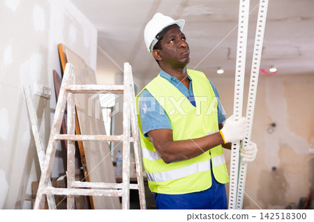 African american builder holds an aluminum profile for interior decoration African american builder holds an aluminum profile for interior decoration 142518300